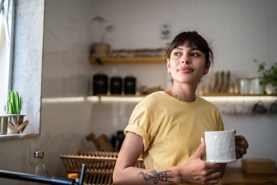 Woman wearing yellow shirt holding a mug.